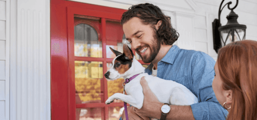 férfi kistestű kutyájával a karjában